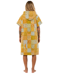 Person wearing a yellow patterned cover-up on a white background