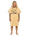A woman stands barefoot against a plain white studio background wearing a tan hooded towel dress with a 'GAY RIGHTS' graphic on the front.