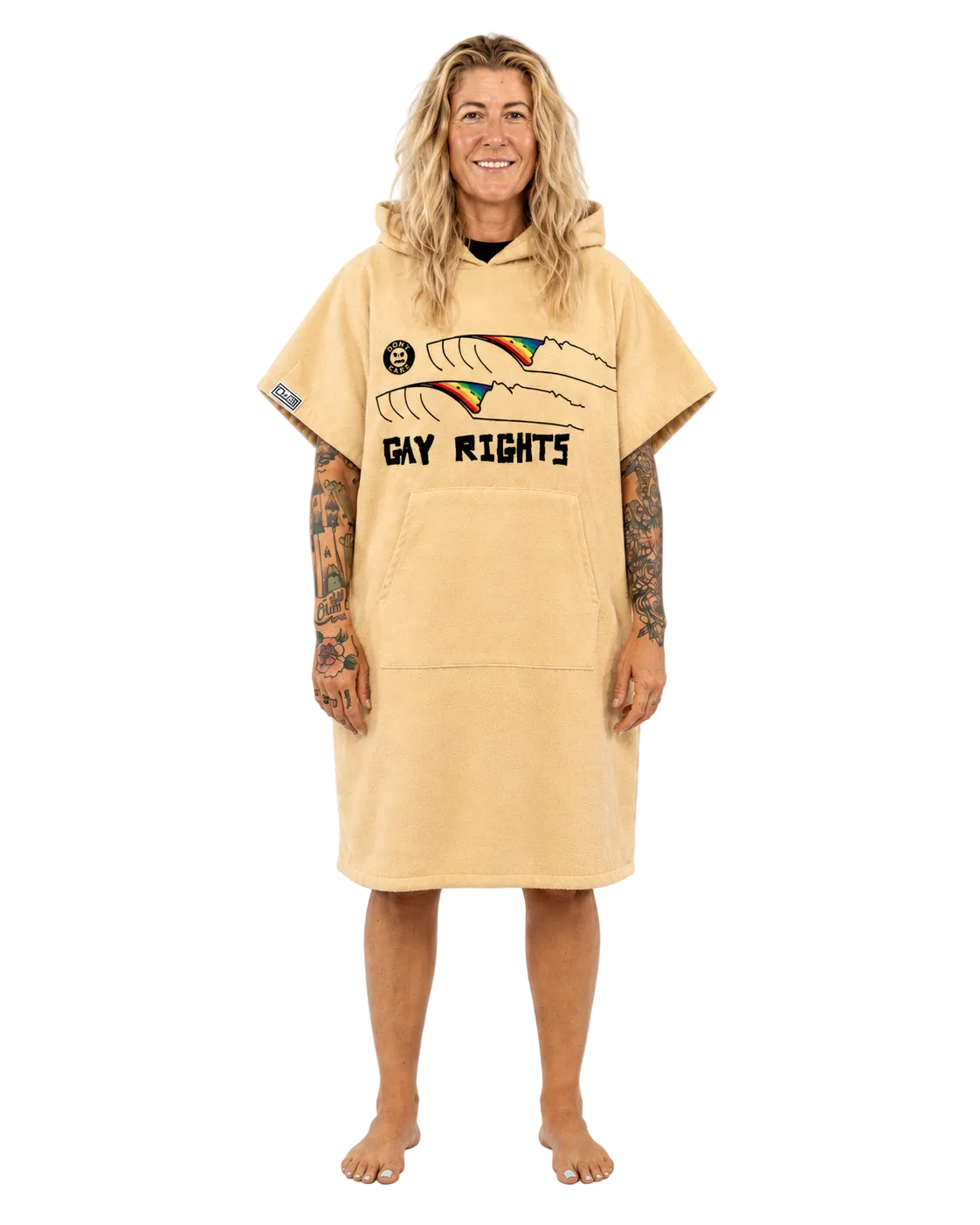 A woman stands barefoot against a plain white studio background wearing a tan hooded towel dress with a 'GAY RIGHTS' graphic on the front.