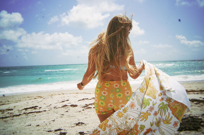 Towel with tropical pattern featuring palm trees, flowers, and landscapes.
